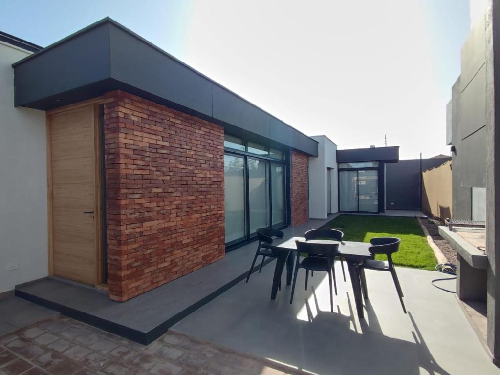 eine Terrasse mit einem Tisch, Stühlen und einer Ziegelwand in der Unterkunft Villa Las Moras in Ciudad Lujan de Cuyo