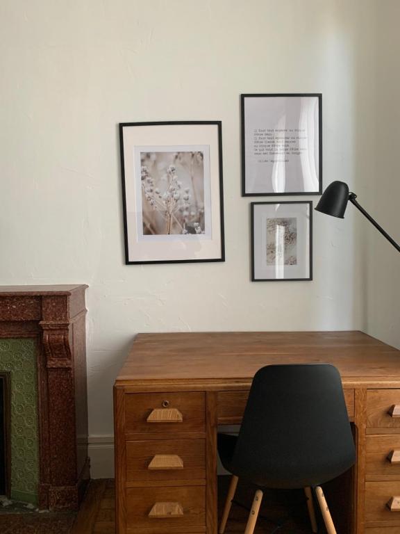 a desk with a black chair and pictures on the wall at les chambres de pauline in Albertville