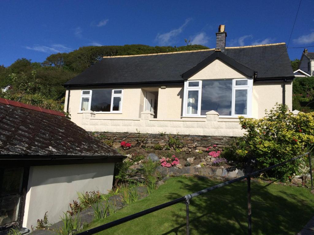 a white house with a black roof at Lovely cottage in Snowdonia, private hot tub, by mountains & award winning beach in Fairbourne