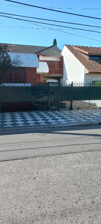 une clôture sur le côté d'une rue avec une maison dans l'établissement Casa Privada Monte Grande y cochera, à Monte Grande