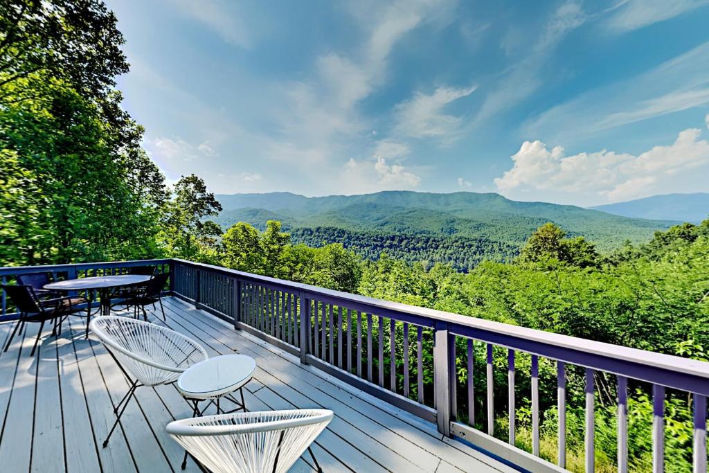 a balcony with tables and chairs and a view of the mountains at Barenberg Cabin - Secluded Unobstructed Panoramic Smoky Mountains View with Two Master Suites, Loft Game Room, and Hot Tub in Gatlinburg