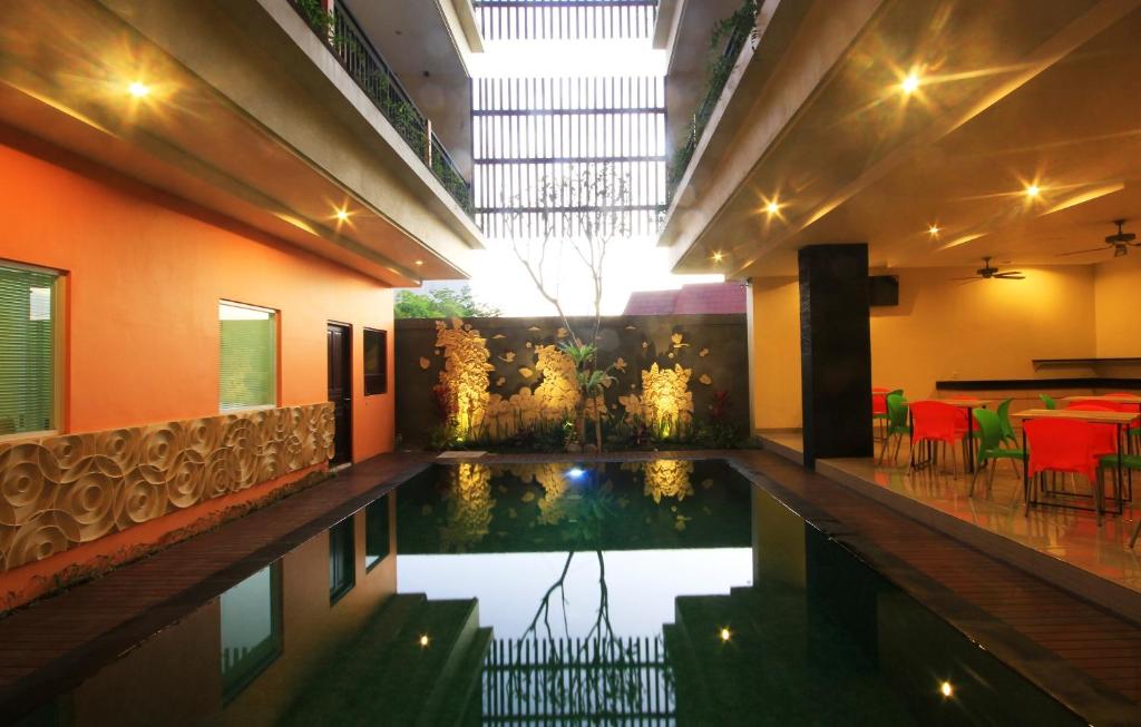 a swimming pool in the middle of a building with tables and chairs at The Agung Residence in Seminyak