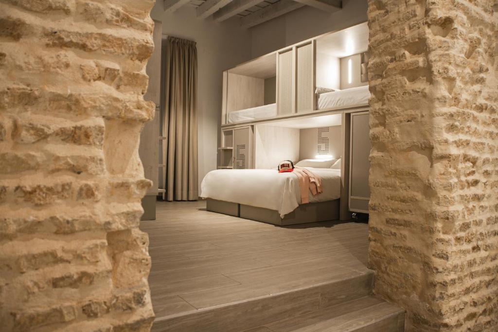um quarto de hotel com uma cama e uma parede de tijolos em room00 Salvador Hostel em Sevilha