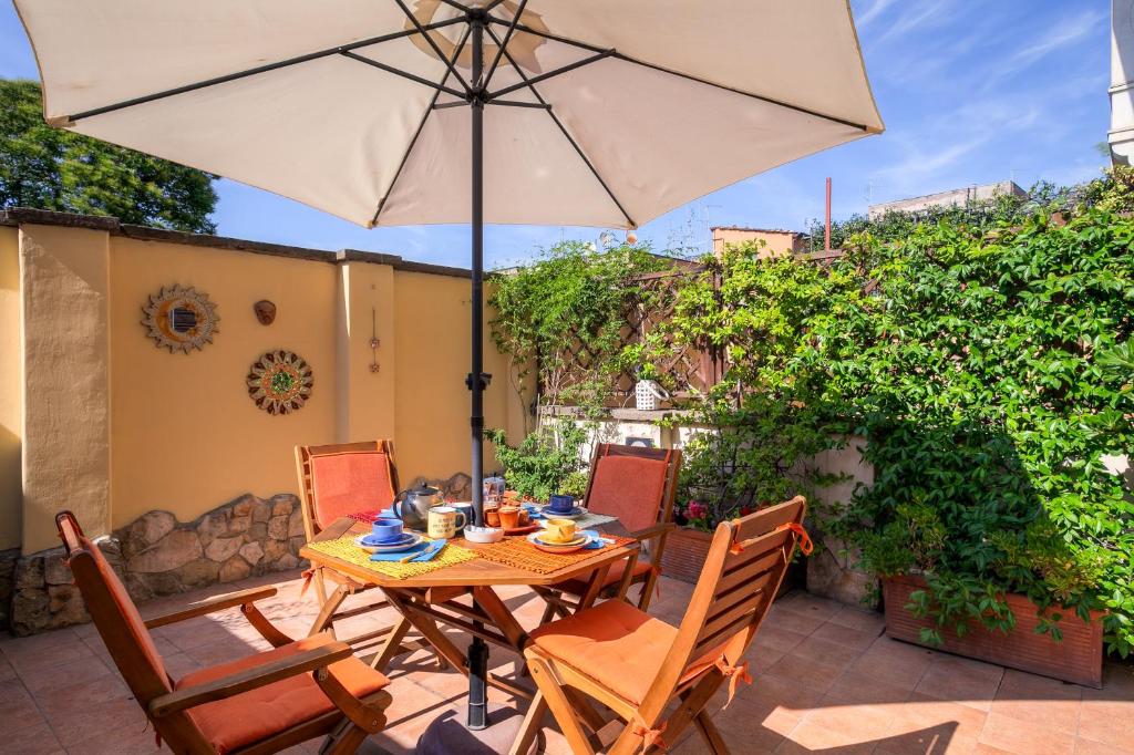 una mesa y sillas con una sombrilla en el patio en Colosseo Residenza Sette Sale, en Roma