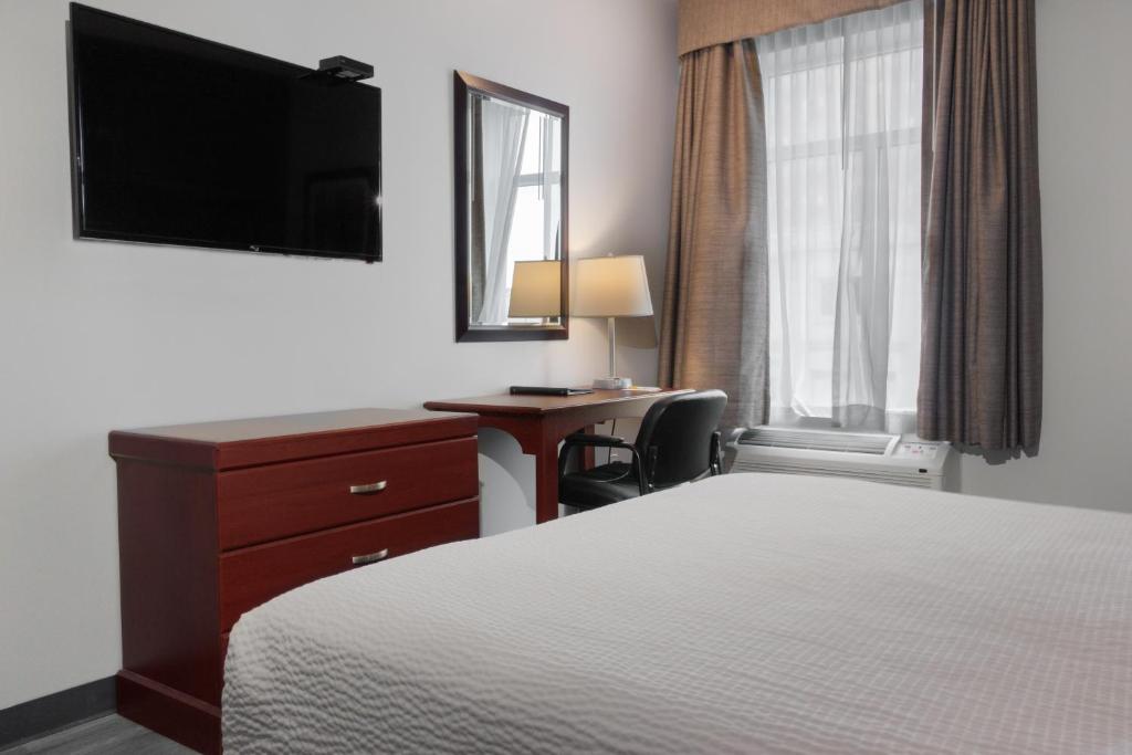 een hotelkamer met een bed, een bureau en een televisie bij Premier Inn & Suites - Downtown Hamilton in Hamilton