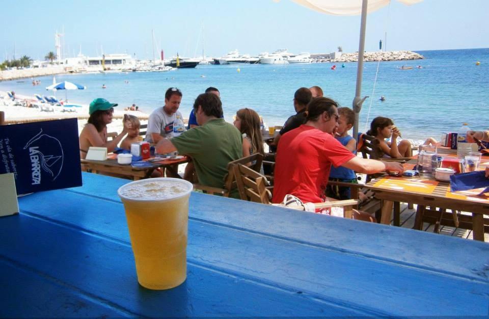 a glass of beer sitting on a blue table at a beach at Apartamento en Altea con vistas al mar in Altea