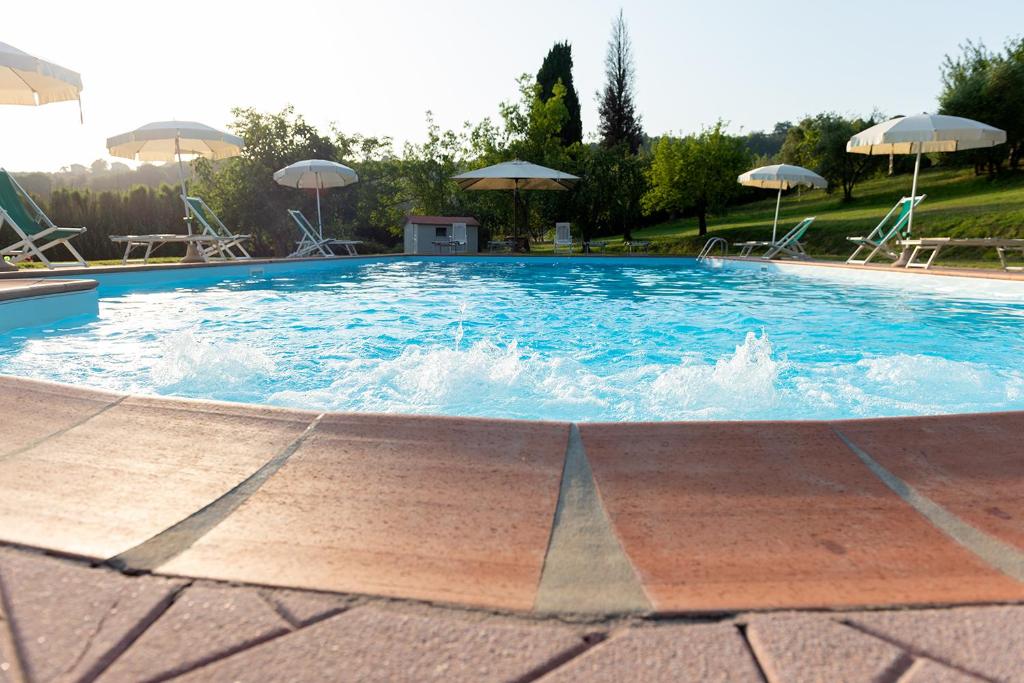 una gran piscina con sillas y sombrillas en Antiqua Vallis, en Palaia