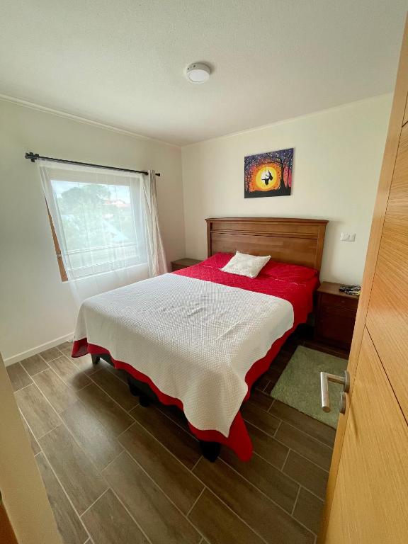 una camera con letto rosso e finestra di Depto a pasos del centro de Puerto Montt a Puerto Montt