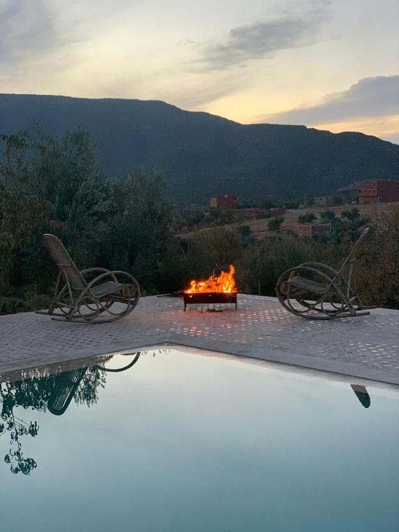 uma fogueira com duas cadeiras ao lado de uma piscina em Dar Khalti - Cascades - Piscine - Montagne em Ouzoud