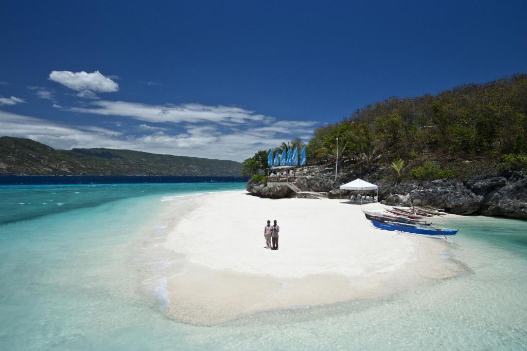 蘇米龍島的住宿－Bluewater Sumilon Island Resort，两个人站在水边的海滩上