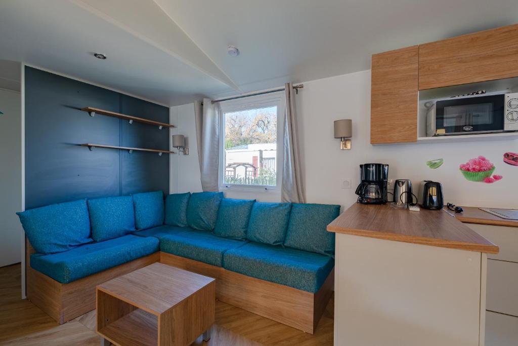 a living room with a blue couch in a kitchen at Mobil Home Manon in Fréjus