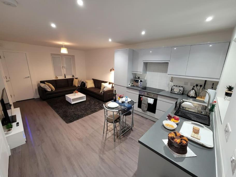 uma ampla sala de estar com uma cozinha e uma sala de estar em New build home with WI-FI, Smart TV, dedicated office floor, large terrace and Free parking em Milton Keynes