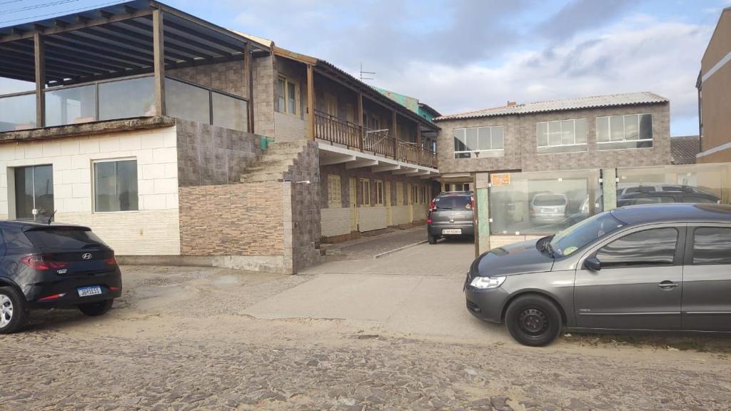 twee auto's geparkeerd op een parkeerplaats naast een gebouw bij Pousada Vila di Italia in Cidreira