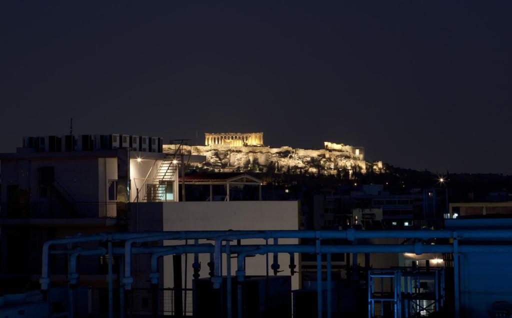 uma vista da acrópole de uma cidade à noite em Hotel Katerina em Atenas