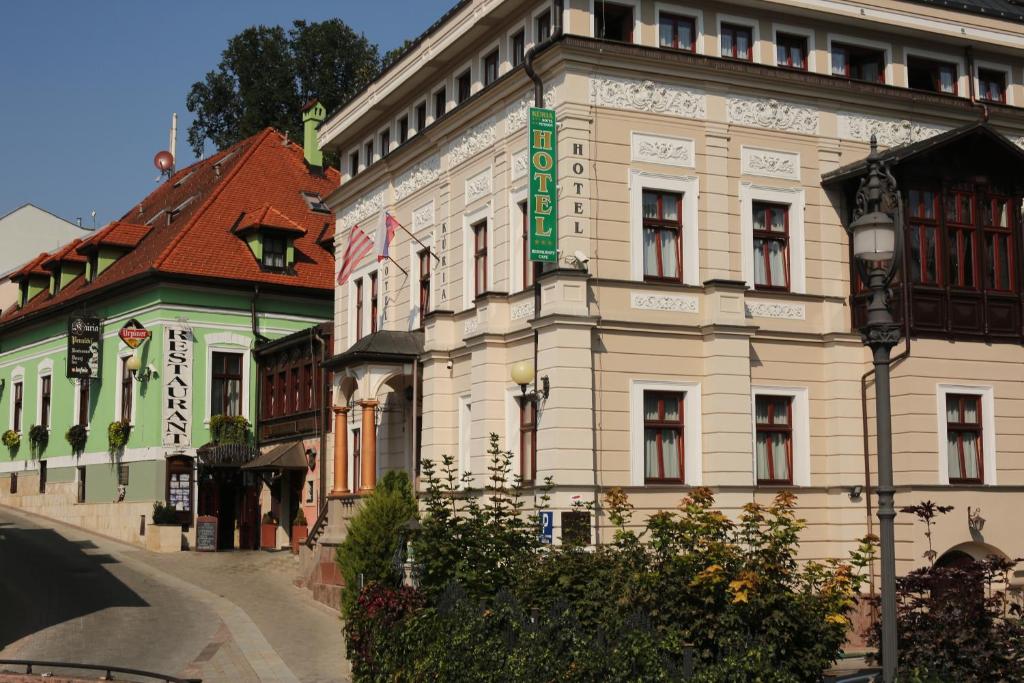 un gran edificio blanco con un letrero verde. en Hotel Kuria en Banská Bystrica