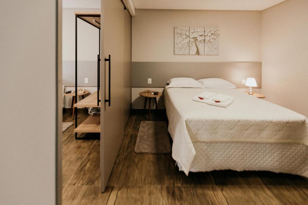 um quarto com uma cama branca e uma casa de banho em CasAlta Pousada em Bento Gonçalves