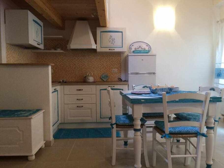 La cuisine est équipée d'une table, de chaises et d'un réfrigérateur. dans l'établissement El Dorado Luxury Apartment, à Alghero