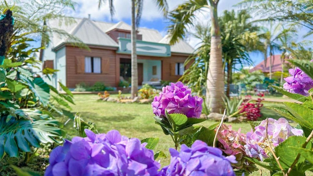 une maison avec des fleurs violettes devant une cour dans l'établissement Magnifique villa créole VILLA TI BOUT BOIS avec cheminée au tevelave, à Les Avirons