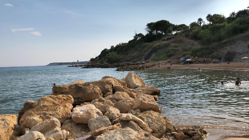 Casa vacanze Capo Rizzuto 3 في Ovile la Marinella: كومة من الصخور على شاطئ قريب من الماء