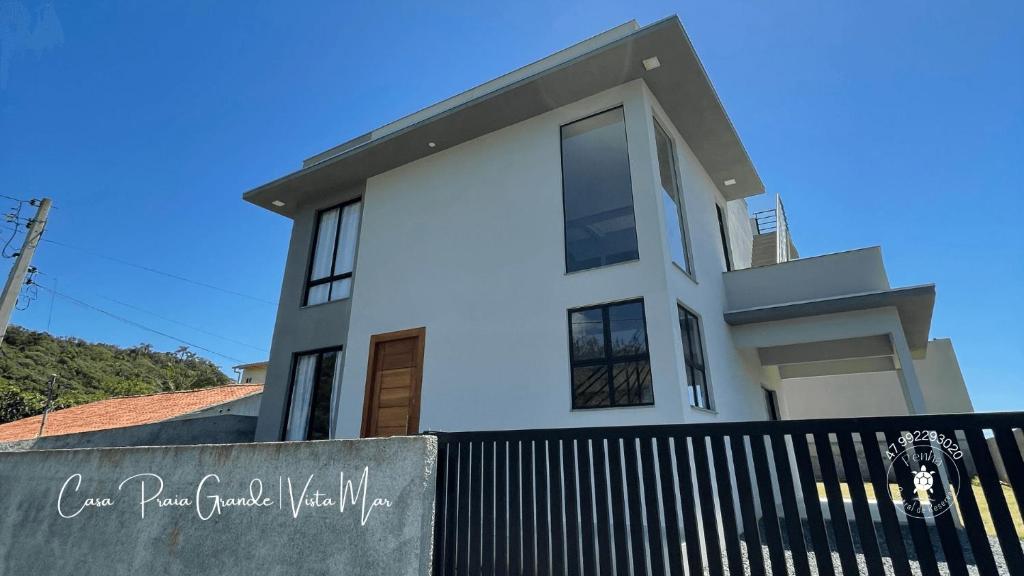 una casa blanca con una valla negra delante de ella en Casa confortável com 2 quartos e 1 suíte, pertinho do Mar, Praia Grande - Beto Carrero, Penha SC, en Penha