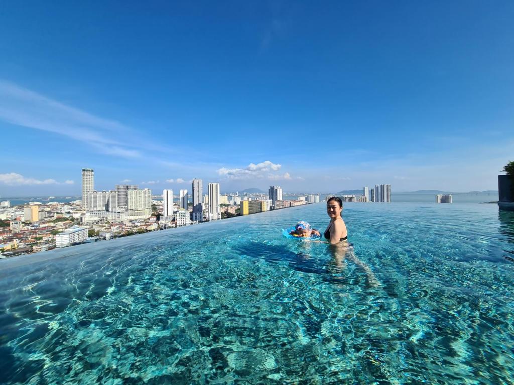 una mujer en la piscina infinita del horizonte de Dubái en Beacon Executive Suites - Penang en George Town