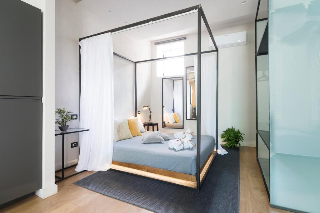 sypialnia z łóżkiem z baldachimem i lustrem w obiekcie Stay In Ortigia w Syrakuzach