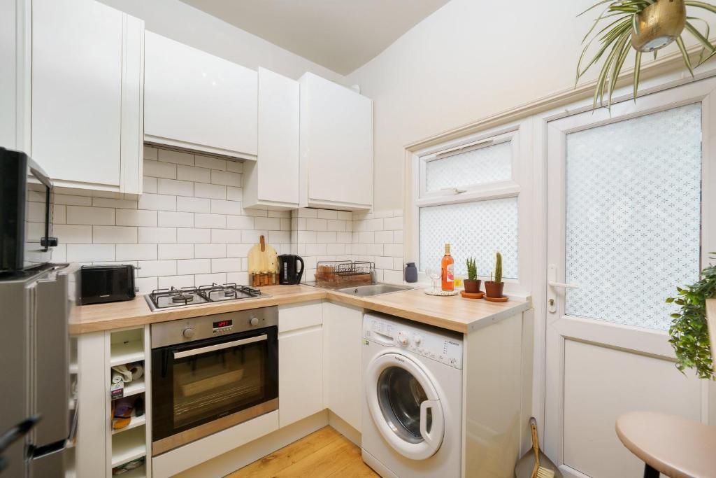 a kitchen with white cabinets and a washer and dryer at Gorgeous apartment Wood Green Palmers Green in Palmers Green