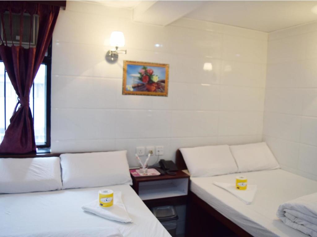 een kamer met 2 bedden en een raam bij Om Guest House in Hong Kong