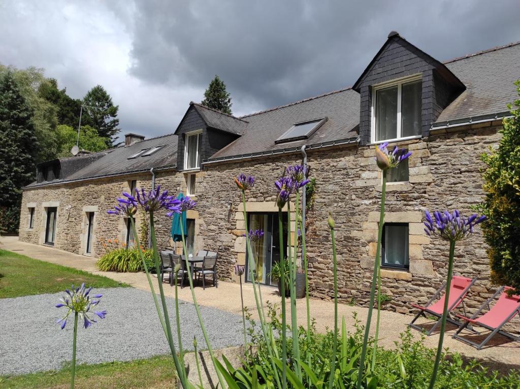 een stenen huis met paarse bloemen ervoor bij Aux Agapanthes in Pluherlin