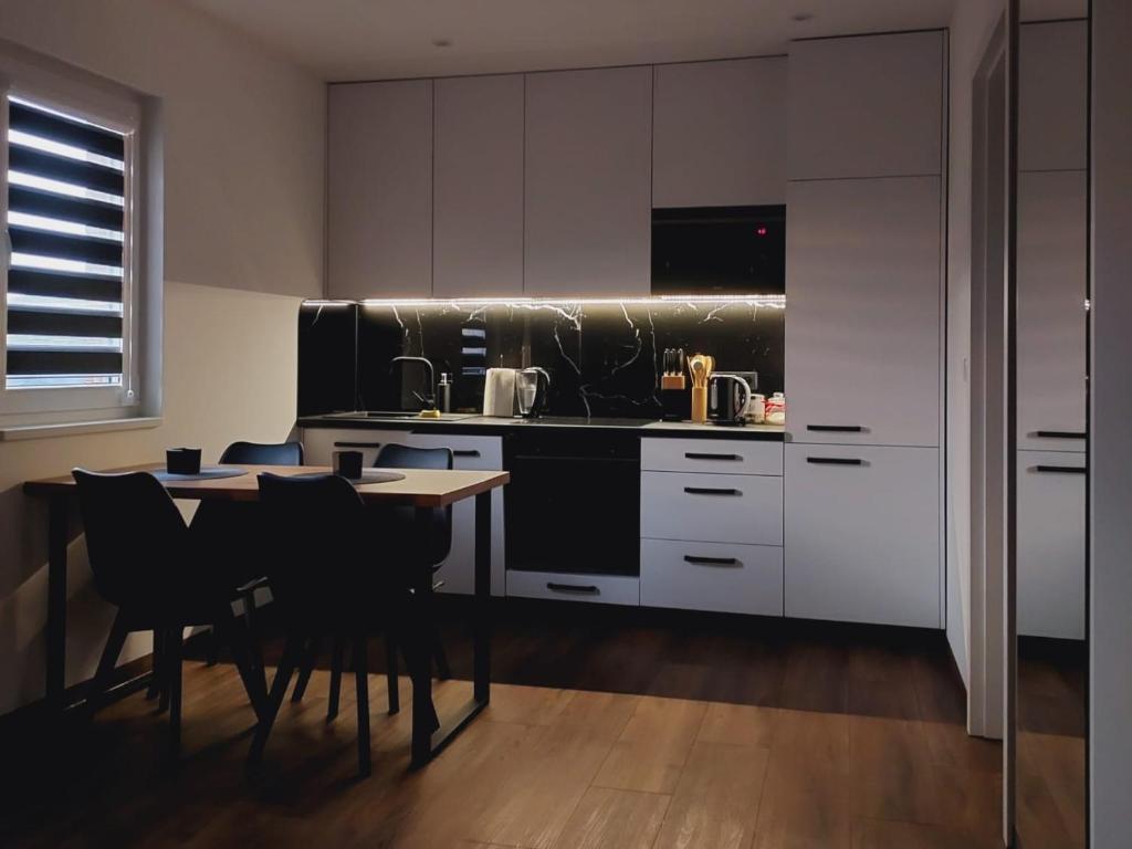 uma cozinha com armários brancos e uma mesa com cadeiras em Luxury Apartments Bernardyńska Domek 1 , 2 em Kielce