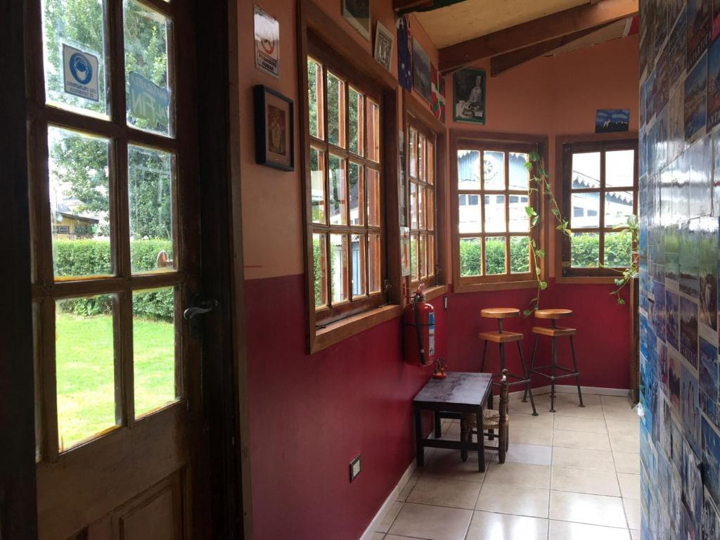 een kamer met een rode muur met een tafel en ramen bij House 1903 in Ushuaia