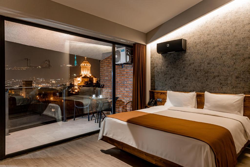 a bedroom with a bed and a balcony with a table at Ivy Hotel in Tbilisi City