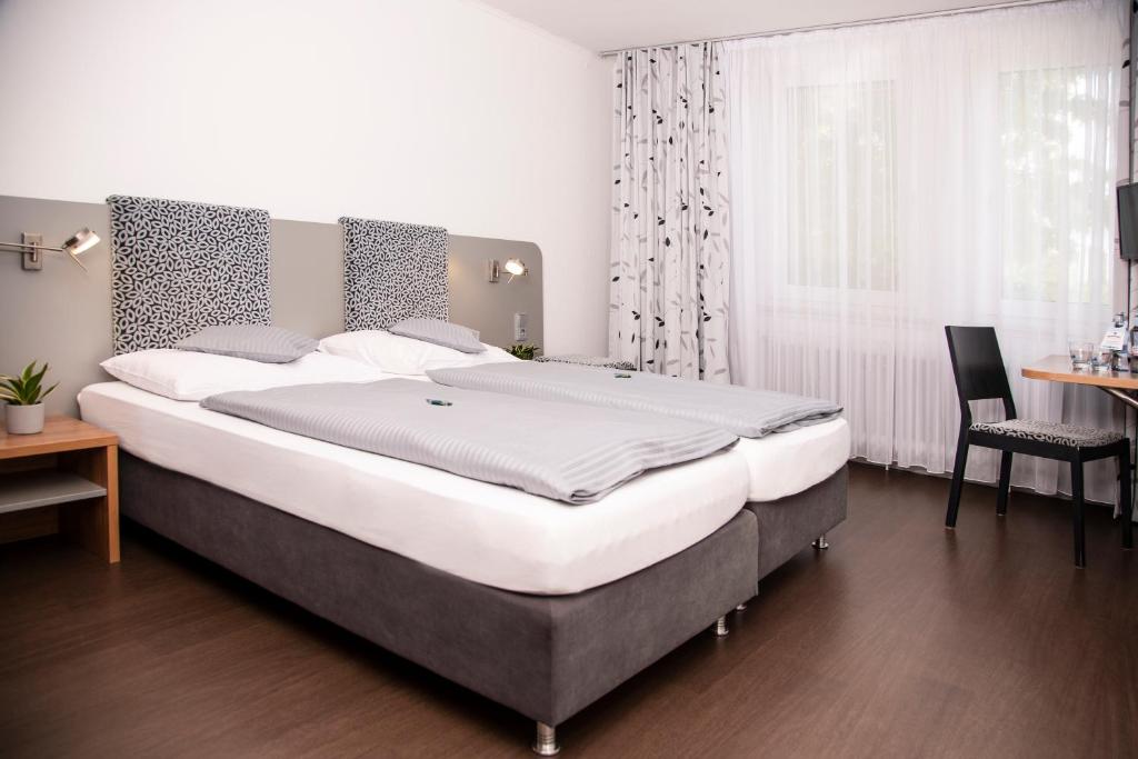 a large bed in a bedroom with a table and a chair at Hotel Russweiher in Eschenbach in der Oberpfalz