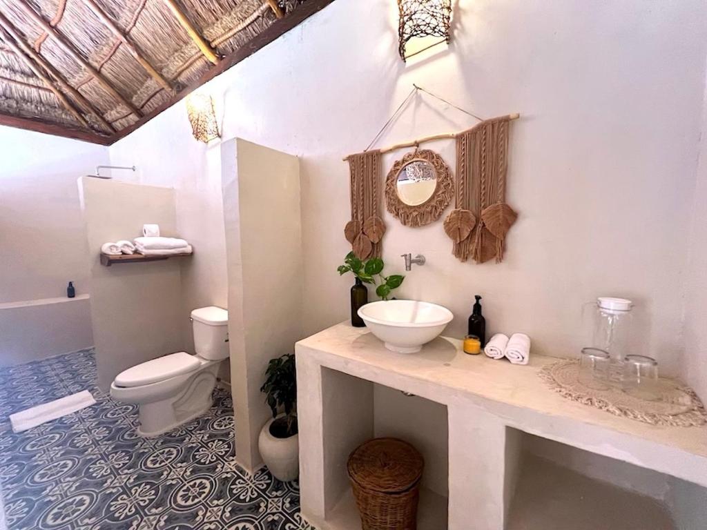 a white bathroom with a sink and a toilet at Tzunum Jade in Tulum