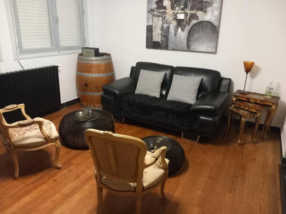 - un salon avec un canapé noir et des chaises dans l'établissement Maison cosy - 4 chambres doubles, à Bergerac