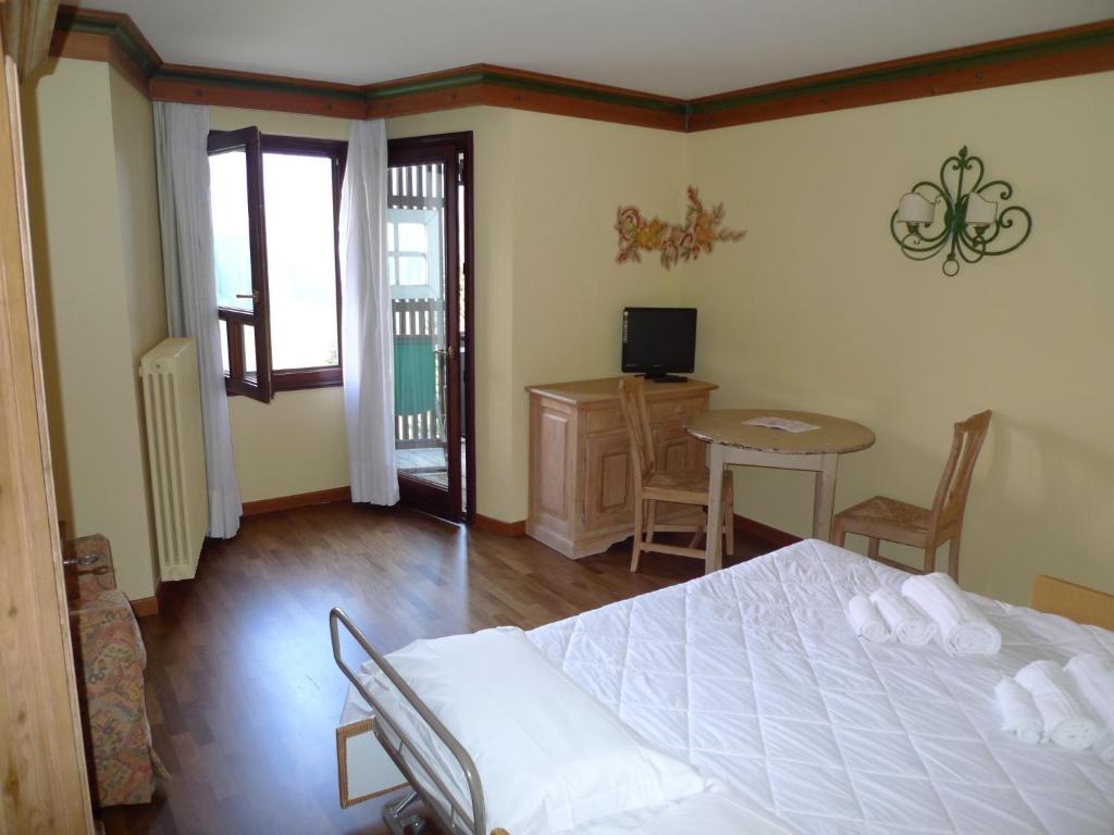 sypialnia z białym łóżkiem, stołem i krzesłami w obiekcie RTA Hotel Catturani w Madonna di Campiglio