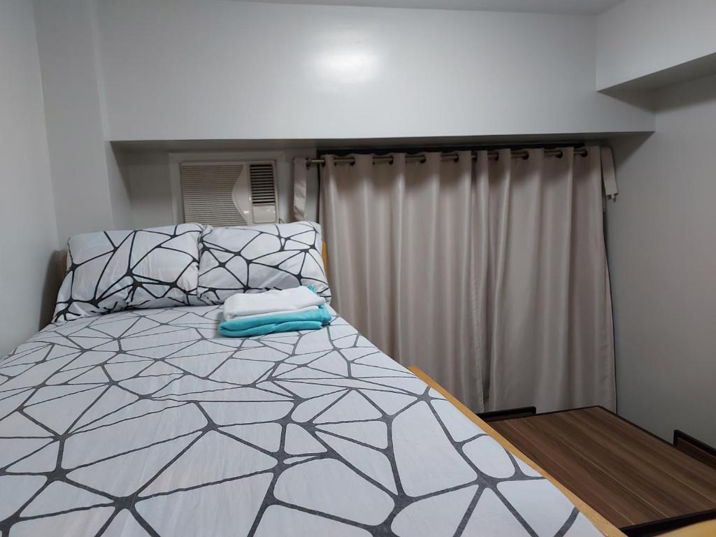 1 dormitorio con 1 cama con edredón gris y blanco en Bunked Bed Room Sharing, en Manila