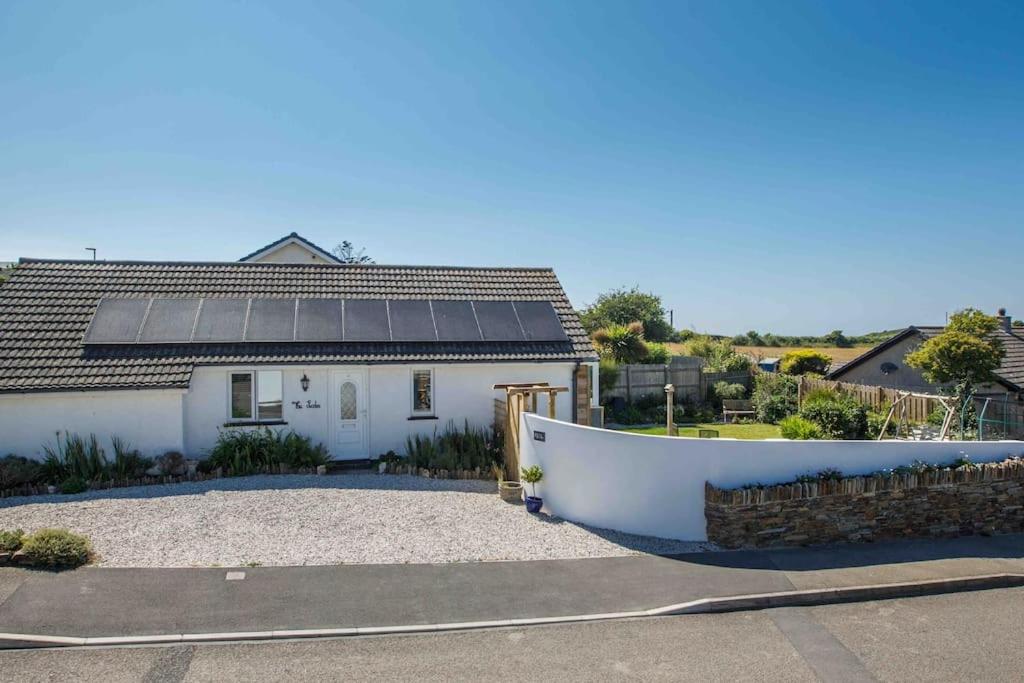 a white house with solar panels on the roof at The Lodge in the heart of Boscastle. in Boscastle