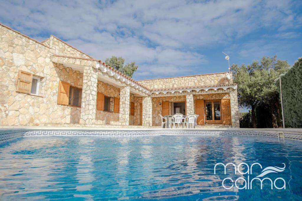 a villa with a swimming pool in front of a house at Villa La Roca by MarCalma in Les tres Cales