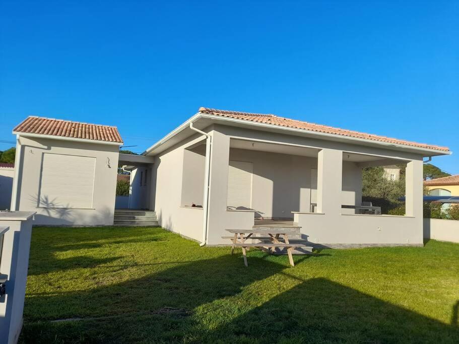 een wit huis met een picknicktafel in de tuin bij Villa avec piscine chauffée entre terre et mer in Folelli