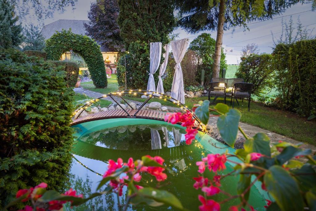 un jardín con un estanque con un puente y flores en Apartments Ladka, en Begunje na Gorenjskem