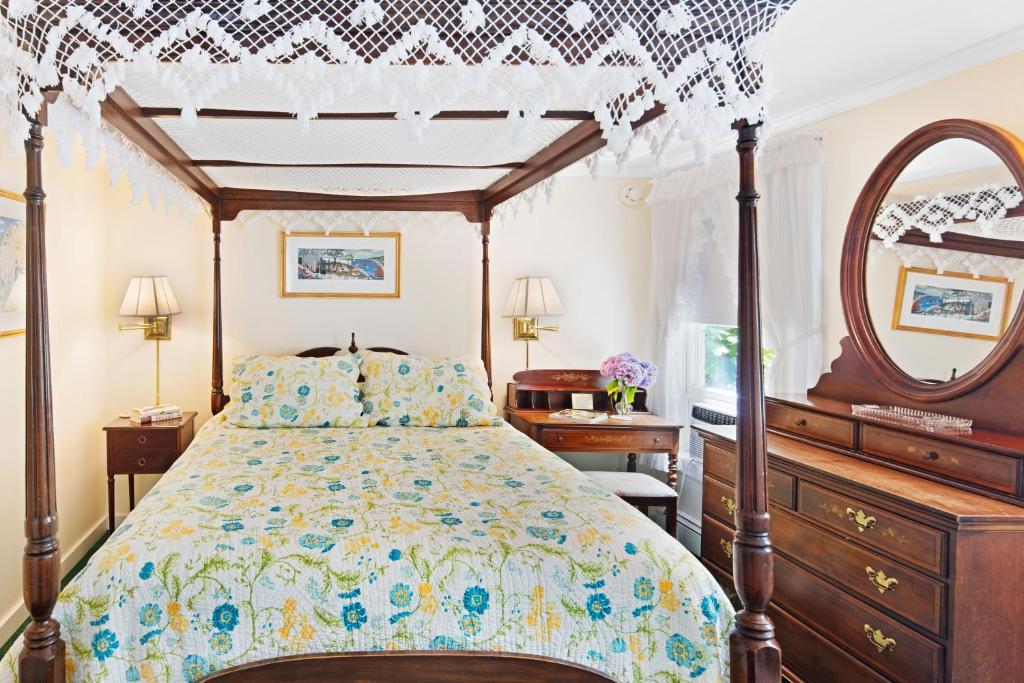 um quarto com uma cama, uma cómoda e um espelho em The Lightkeeper’s Inn em Edgartown