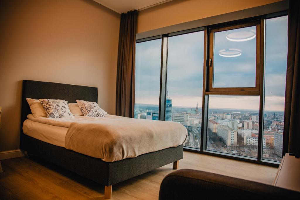 een slaapkamer met een bed en een groot raam bij JBHotels Apartament Premium Hanza Tower in Szczecin