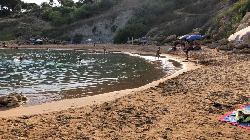 une plage avec un groupe de personnes nageant dans l'eau dans l'établissement ApartHotel Capo Rizzuto, à Ovile la Marinella