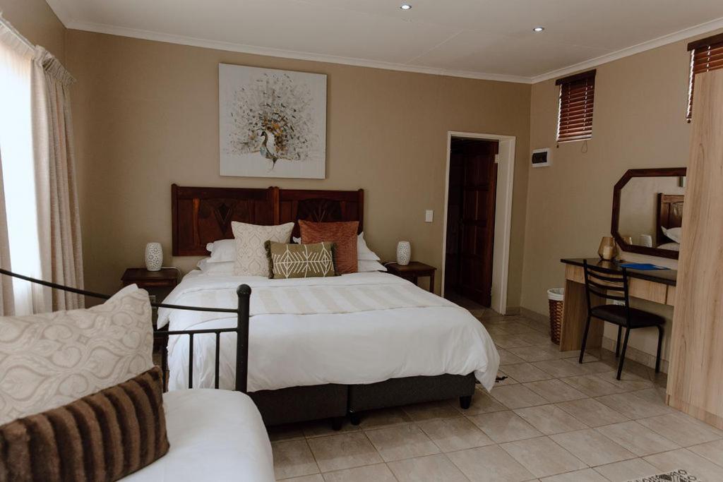 a bedroom with a large bed and a desk at Marjaniek Wedding Venue & Guest House in Rietfontein