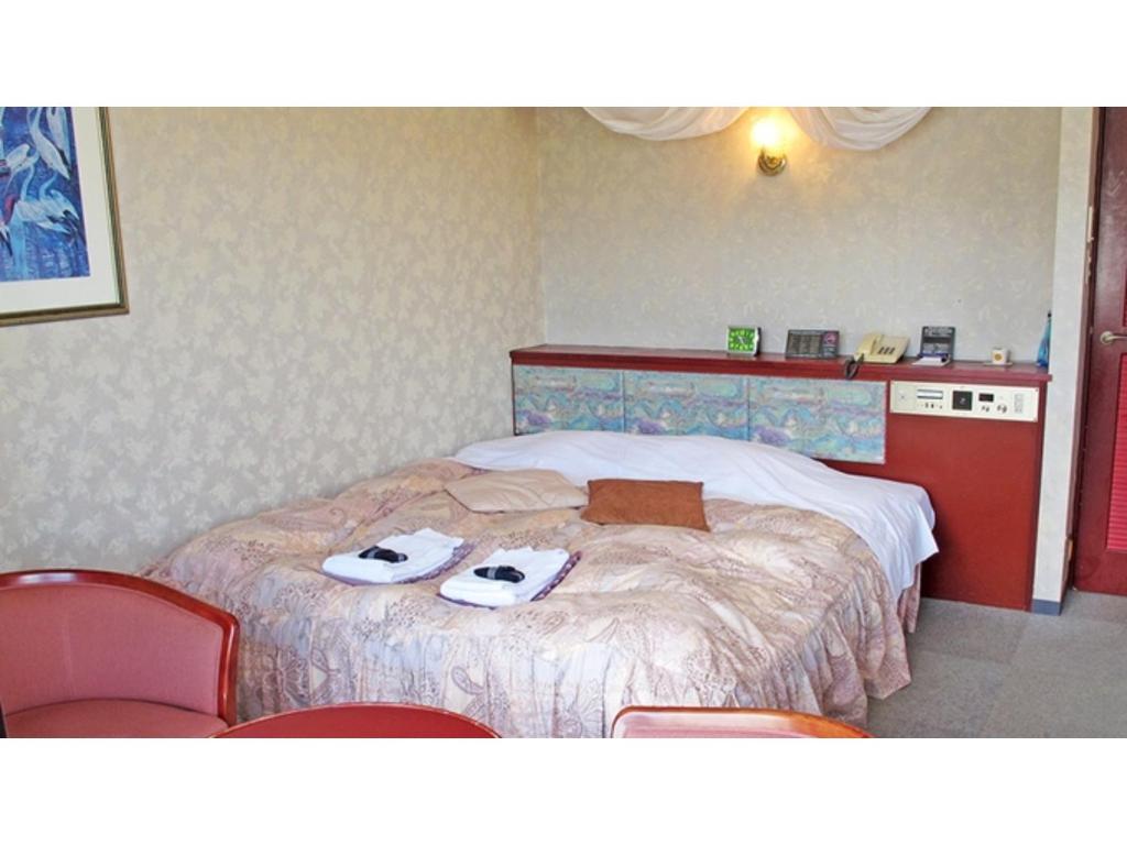 Hotel Platon - Vacation STAY 62234v في Chikuma: غرفة فندق عليها سرير وحذيين