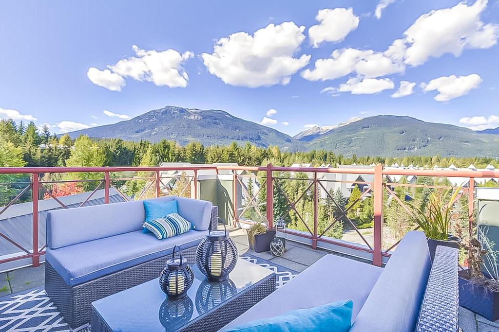 a patio with a couch and a table and mountains at Alpenglow Lodge by Elevate Vacations in Whistler