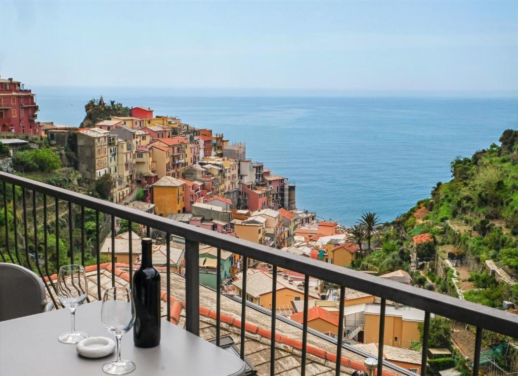 una mesa con copas de vino en un balcón con vistas al océano en Il Bordone - appartamento con vista mare en Manarola