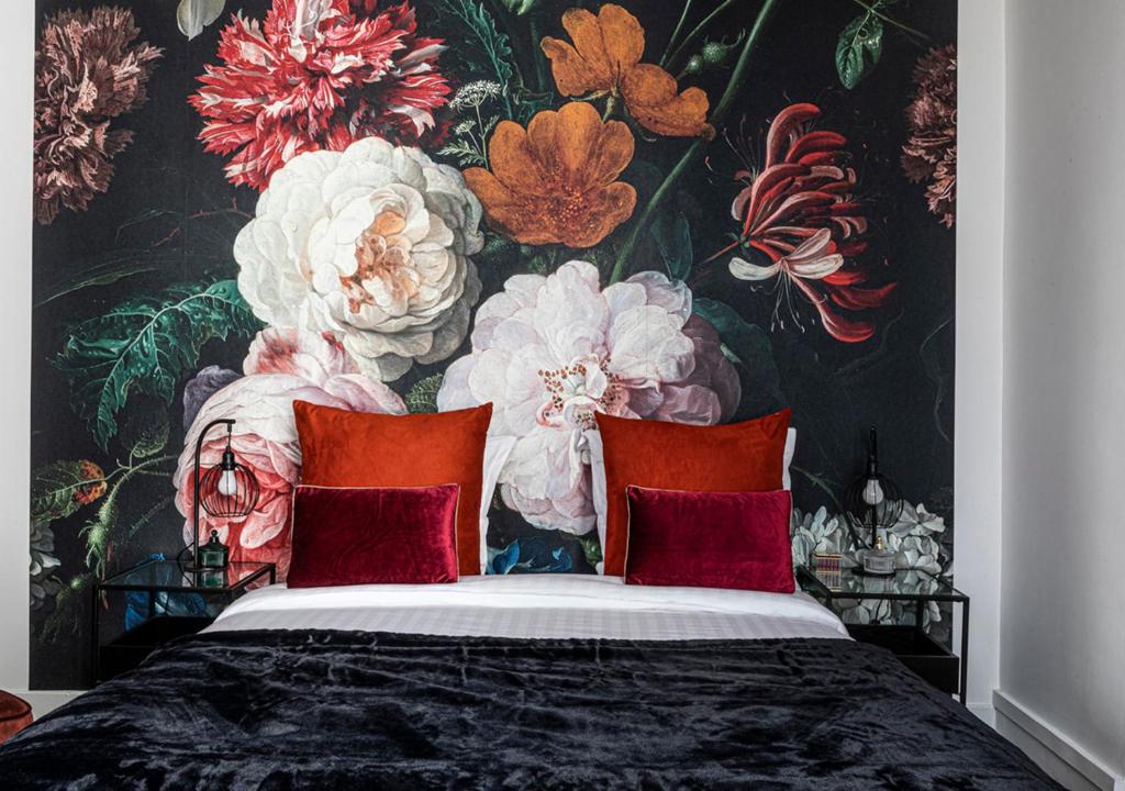 a bedroom with a floral wallpaper with a bed with red pillows at 123paris city in Paris