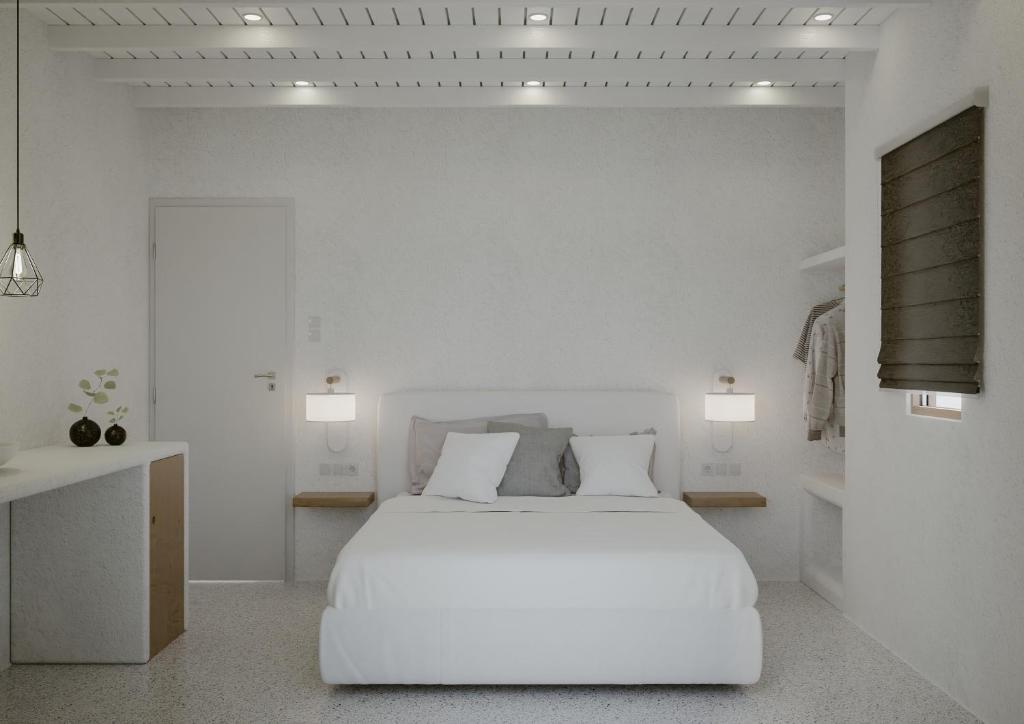 a white bedroom with a white bed and two lights at Alana Mykonos in Mýkonos City